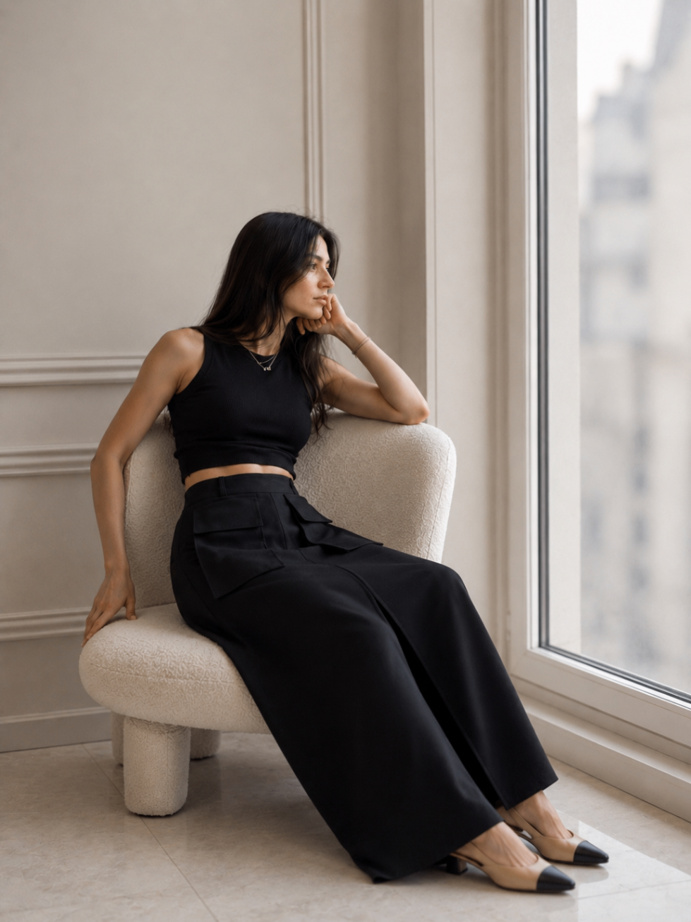 AI fashion frame: black tank and long skirt seated in boucle chair
